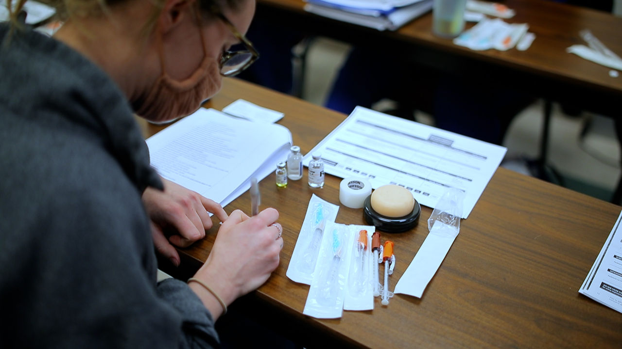 Student Practicing Medical Injection Techniques in Classroom